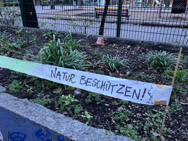 Ein handgemachtes Banner mit dem Text „Natur beschützen“ auf den frisch bepflanzten Hochbeeten vor dem Spielhaus, Sesenheimer Straße.